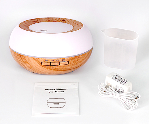 Aromapod ultrasonic nebulizer with wood-grain base and white top, shown with measuring cup and power cable